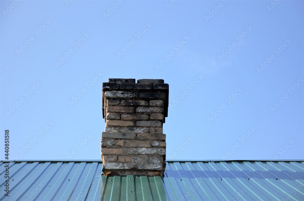 brick chimney on the roof of the house against the blue sky brick chimney on the roof of the house against the blue sky