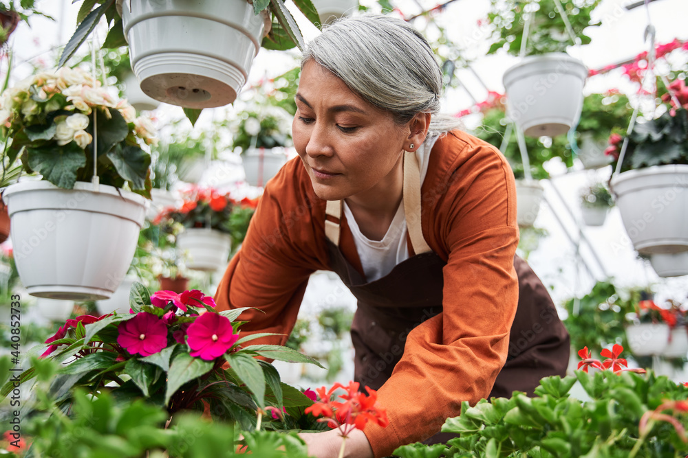 Woman looking at the flowers with tenderness while taking care of it at the greenhouse
