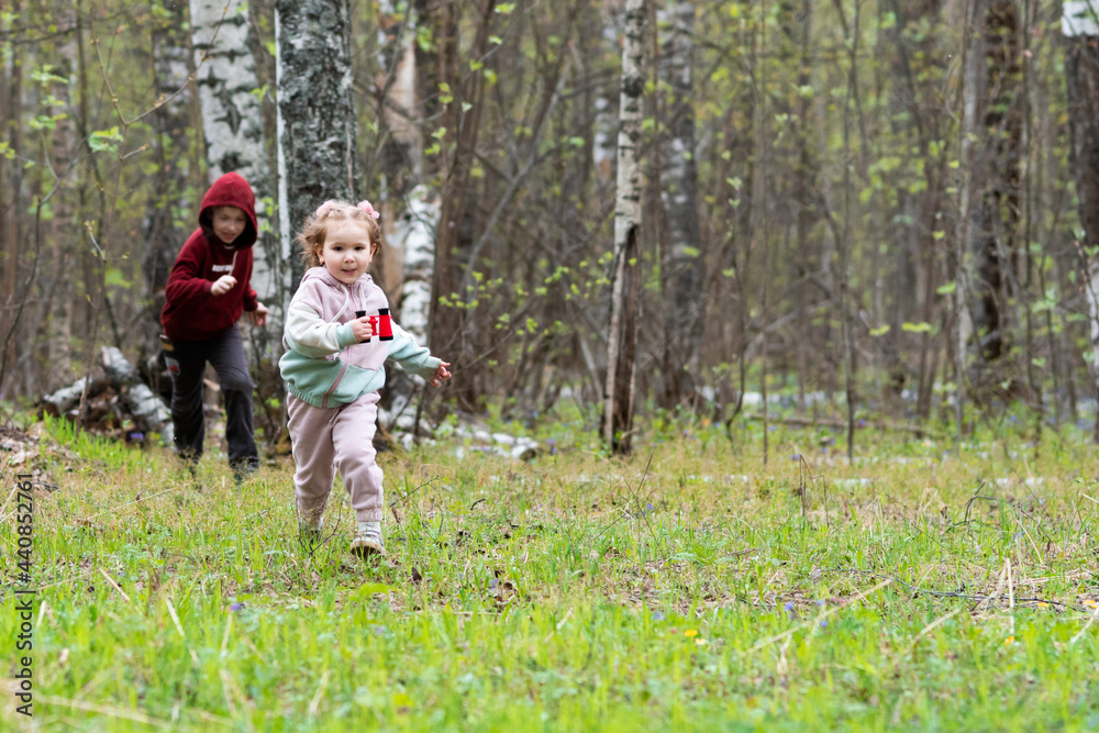 brother and sister run a race in a clearing in the forest