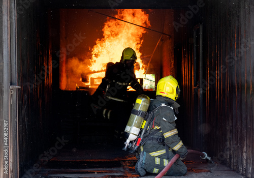 Two firefighters of fireman try to extinguish the fire in container during the practice of their job.