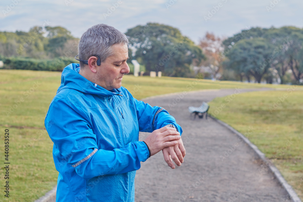 Fototapeta premium Young adult male, wearing, preparing his watch to start running training.