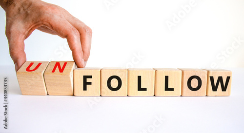 Follow or unfollow symbol. Businessman turns wooden cubes and changes words follow to unfollow. Beautiful white background, copy space. Business and follow or unfollow concept. photo