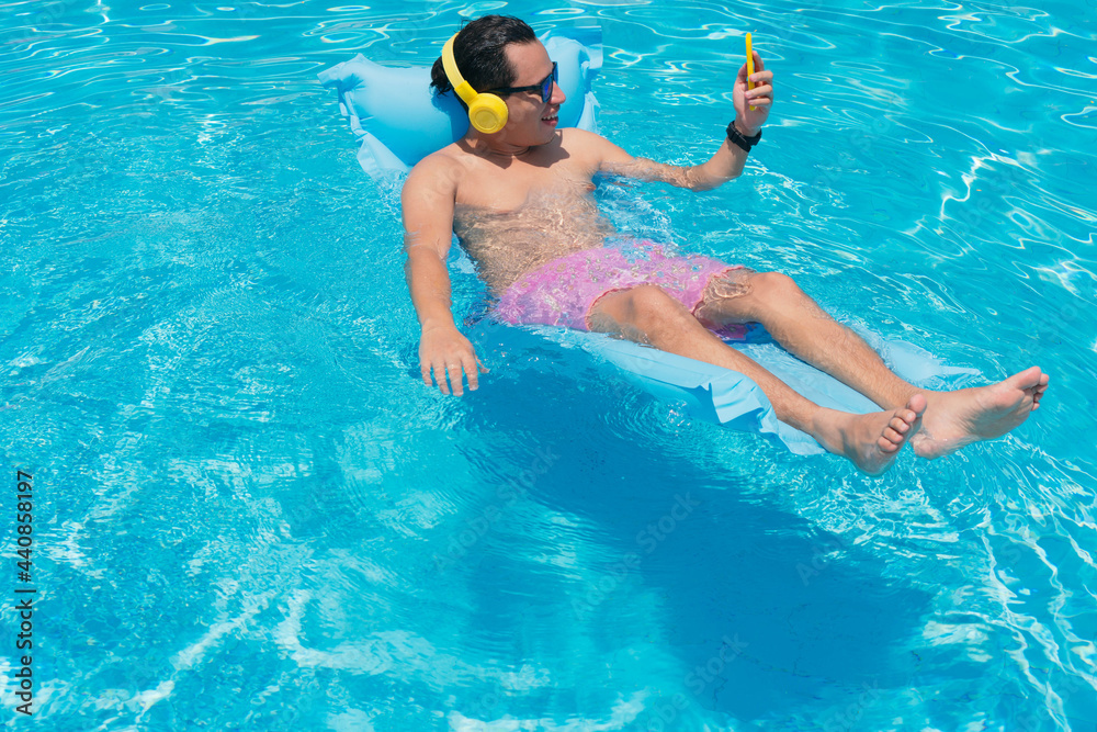 Young man at the swimming pool using his cell phone.