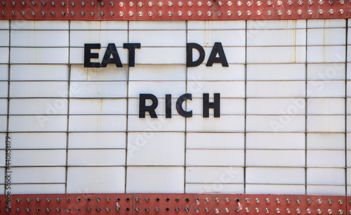 Old marquee sign with 'eat da rich' on it in big black letters