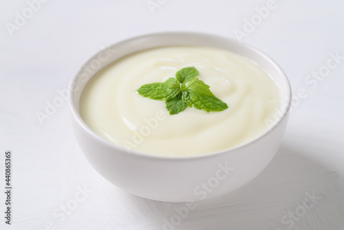 Yogurt in a bowl with mint leaf on white background, Healthy food