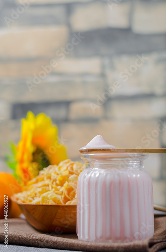 yogurt with natural glutem-free wheat cereal, with fresh orange fruits in a glass cup and a wooden bowl. with copyspace room for text. Greek photo