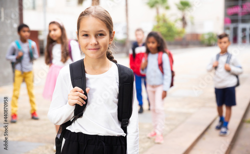 Portrait of smiling tween schoolgirl with backpack on her way to school on autumn day. Back to school concept.