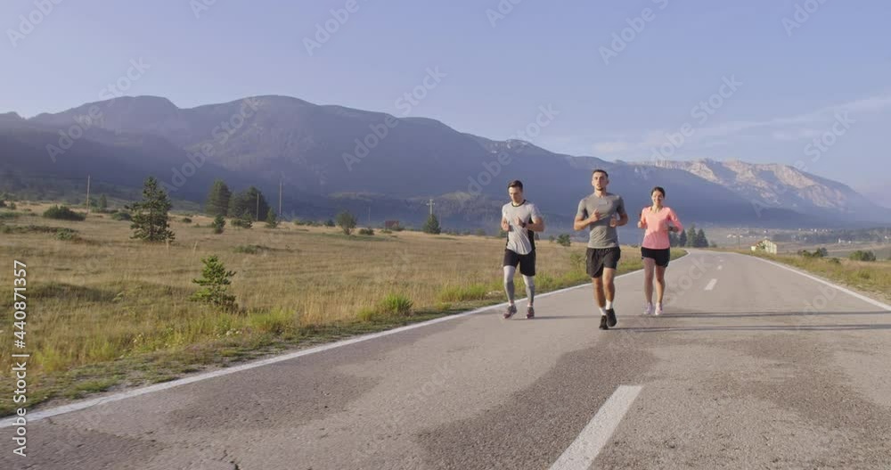Multiethnic group of athletes running together on a panoramic countryside road. Diverse Team of joggers on morning training. Multiethnic group of athletes running together on a panoramic countryside road. Diverse Team of joggers on morning training.
