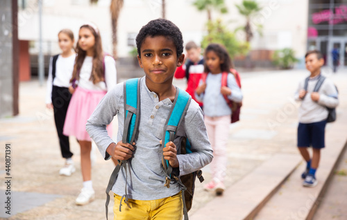 Portrait of African american tweenager walking outside school building on autumn day, going to lessons.