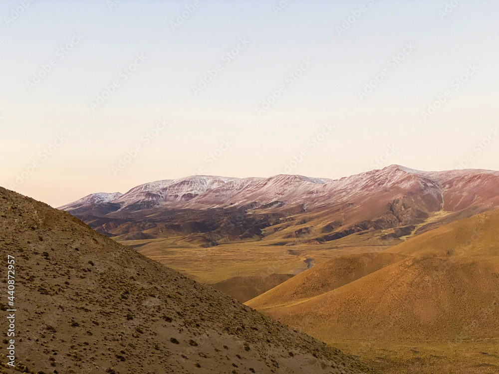 dirt road passing through a barren desert, valley between small mountains, yellow mountains