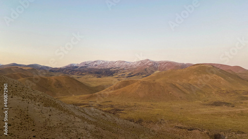 dirt road passing through a barren desert, valley between small mountains, yellow mountains
