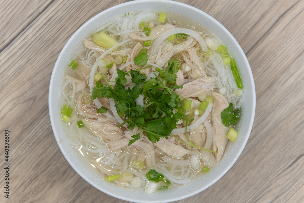 Overhead view of hearty bowl of Chicken Pho loaded with meat, broth, and topped with a sprig of cilantro for a complete meal Overhead view of hearty bowl of Chicken Pho loaded with meat, broth, and topped with a sprig of cilantro for a complete meal
