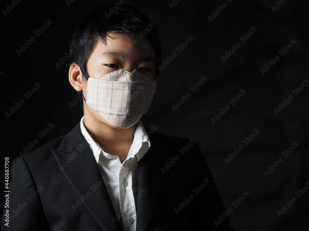 Asian boy wear black suit with mask to protect himself from coronavirus Asian boy wear black suit with mask to protect himself from coronavirus