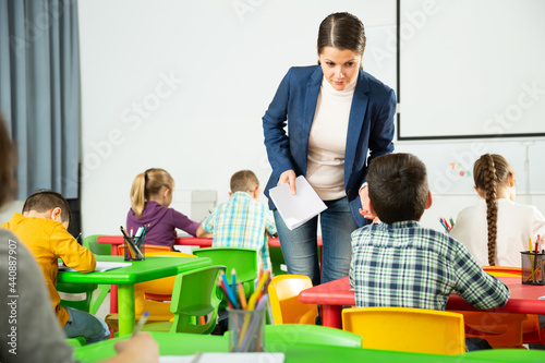 Portrait of young woman teacher at lesson with diligent school kids..