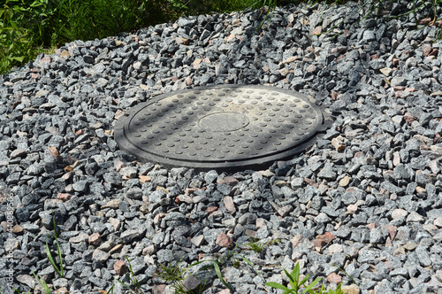 A close-up of a plastic septic tank manhole cover, manhole lid that covers a sewage tank with gravel rocks around. photo