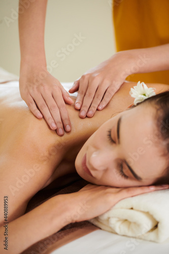 Young woman relaxing while therapist massaging her back