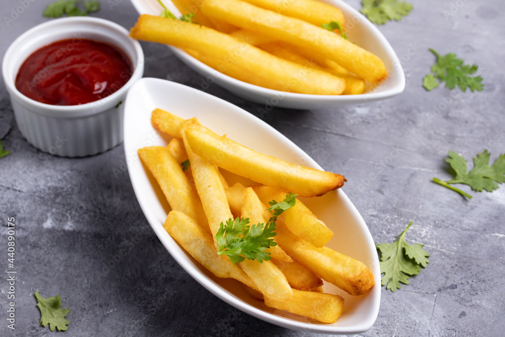 French fries with ketchup in white ceramic cup on gray background French fries with ketchup in white ceramic cup on gray background