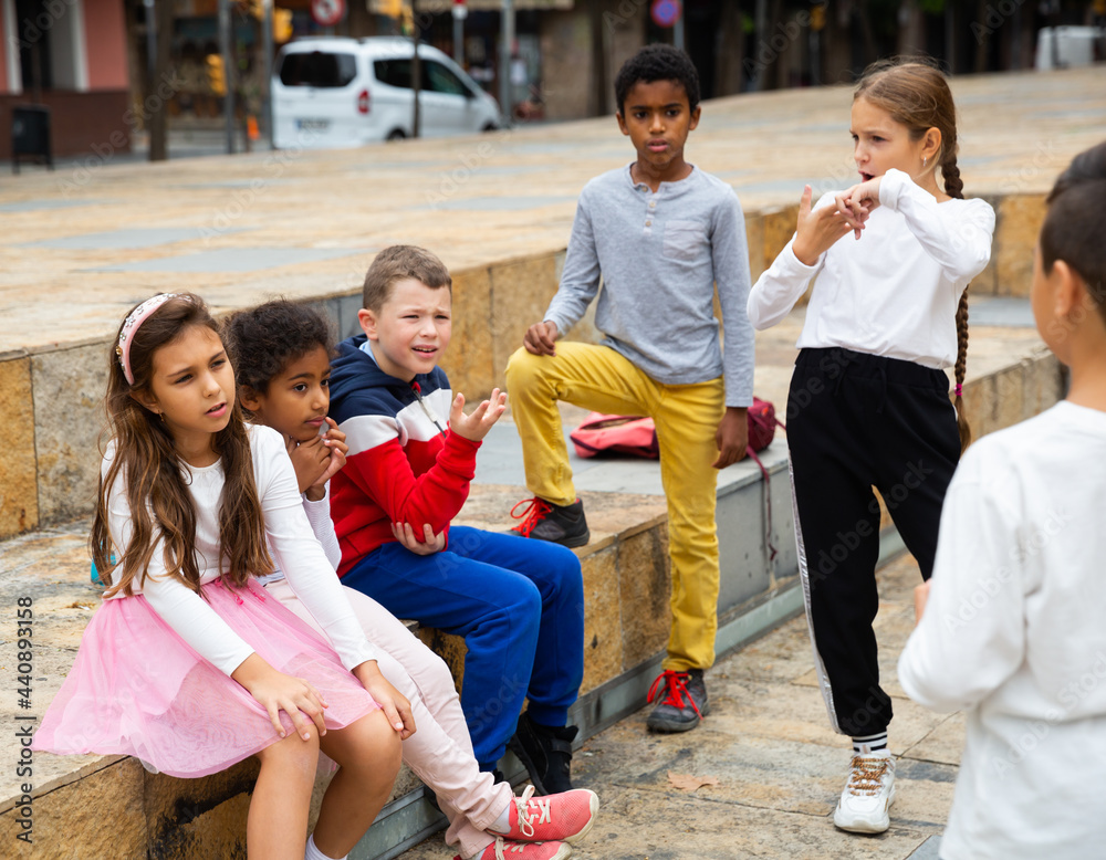 Obraz premium Happy tween boys and girls having friendly discussion during gathering outdoors on autumn day.