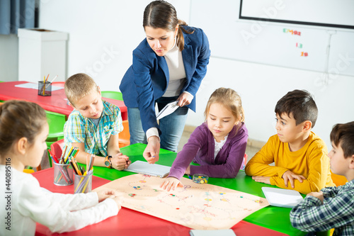 Teacher and pupils play a table game in elementary school class