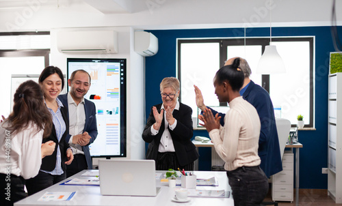 Motivated happy diverse business team people clapping celebrating success at corporate meeting. Multiethnical partners coworkers celebrate successful teamwork result at company briefing
