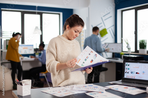 Businesswoman working at her desk in the office checking and analysing report. Executive entrepreneur, manager leader standing working on projects with diverse colleagues.