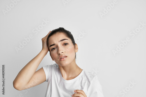 brunette in a white t-shirt holding her head discontent depression pain