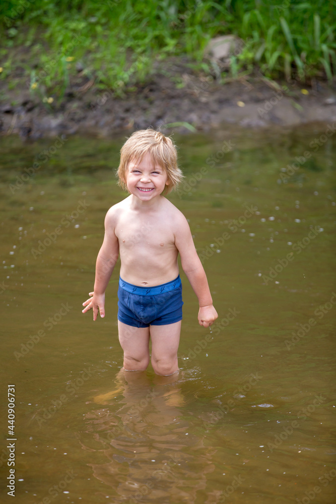 Cute toddler boy, swimming in a pond, smiling at the camera Cute toddler boy, swimming in a pond, smiling at the camera