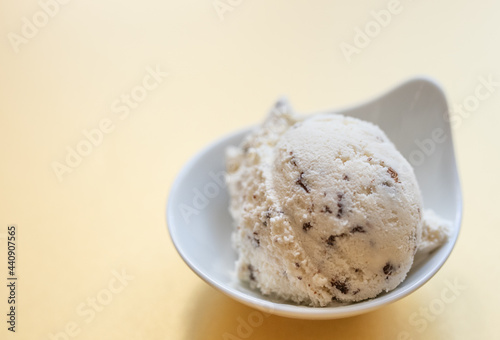 selbstgemachtes Stracciatella Eis mit Ahornsirup, Schokolade mit Kokosblütenzucker, Hintergrund gelb
