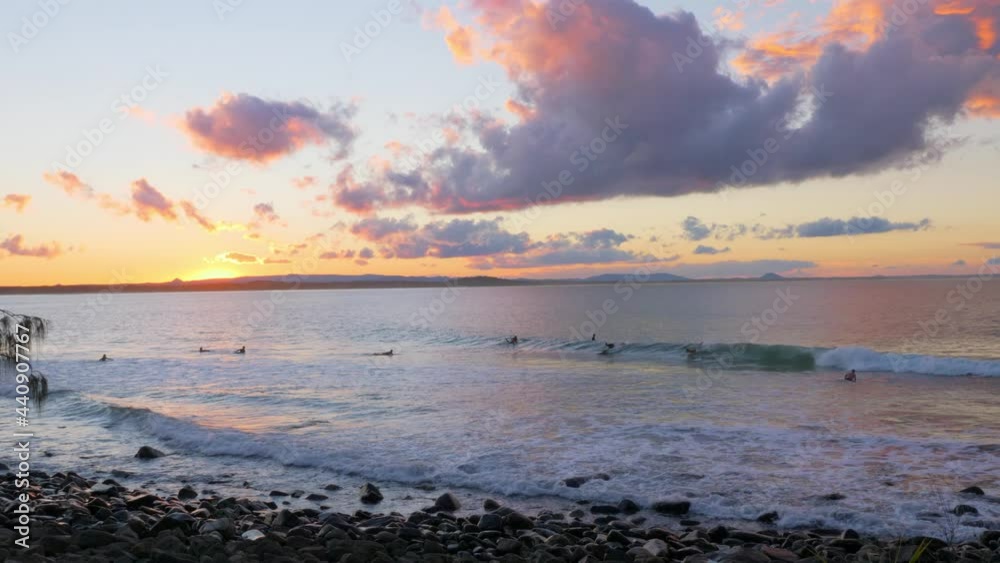 Golden Sunset And Wavy Coast Enjoyed By Surfers At Noosa National Park In Queensland. wide shot Golden Sunset And Wavy Coast Enjoyed By Surfers At Noosa National Park In Queensland. wide shot