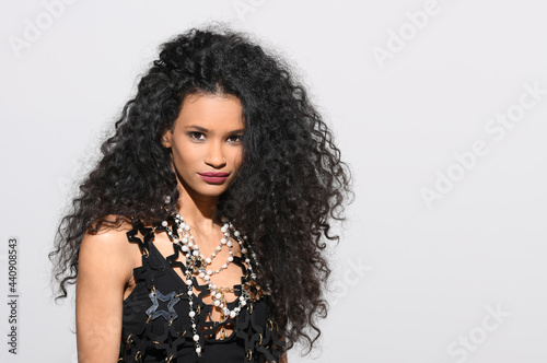 Elegant black woman in a black ensemble with pearl necklace