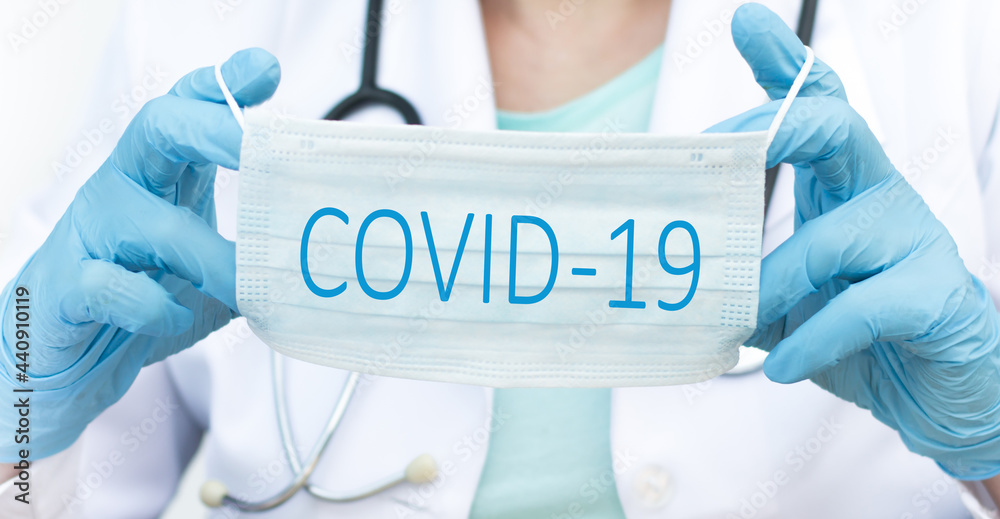 doctor dezhrcht in the hands of a disposable surgical mask with coronavirus text written on it.2019-nCoV virus infection in Wuhan city. Covid-19 spread around the world. Impact of pandemic virus. doctor dezhrcht in the hands of a disposable surgical mask with coronavirus text written on it.2019-nCoV virus infection in Wuhan city. Covid-19 spread around the world. Impact of pandemic virus.