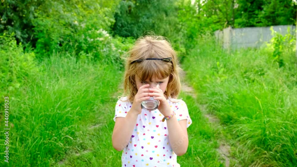 The child drinks water from a glass. Selective focus. The child drinks water from a glass. Selective focus.