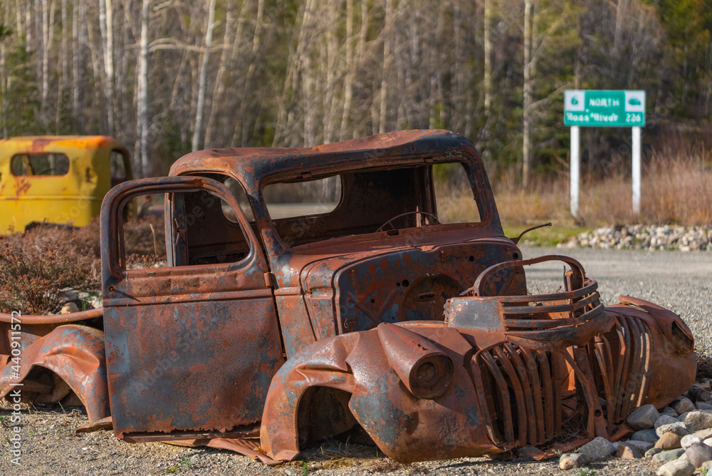 Abandoned rusty 1940s style truck sitting in the wilderness of Yukon Territory during summer time with yellow, rust colored theme and boreal forest in background. Abandoned rusty 1940s style truck sitting in the wilderness of Yukon Territory during summer time with yellow, rust colored theme and boreal forest in background.