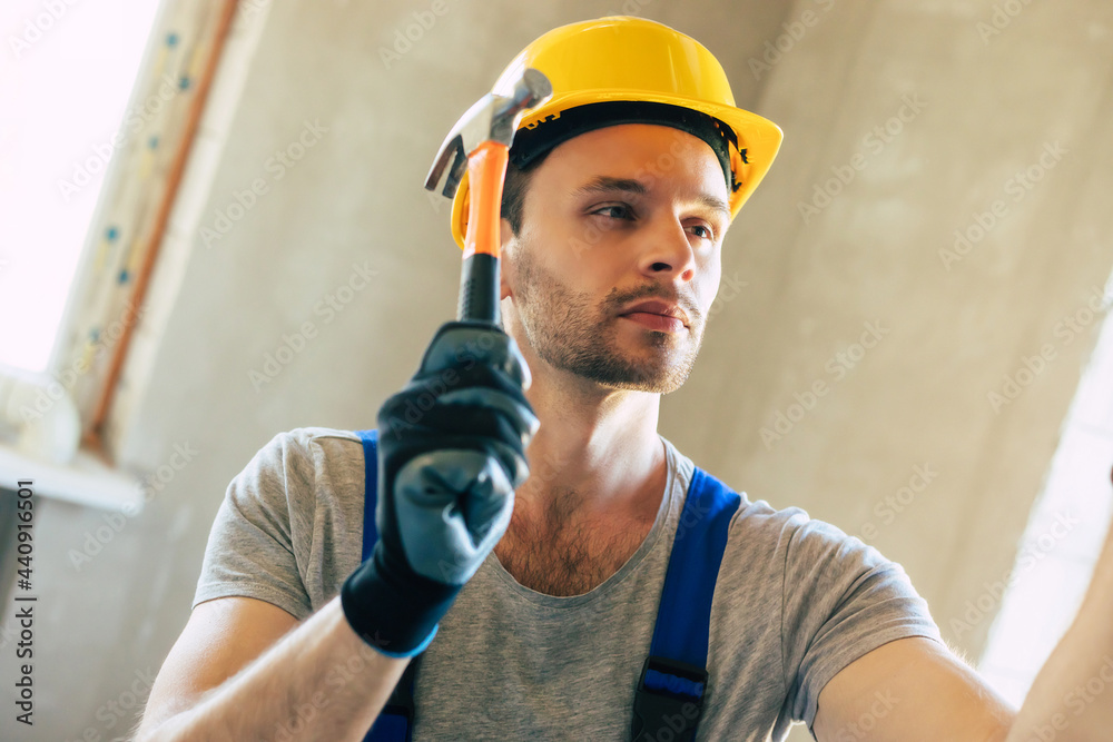 Young home repair male or worker busy with house renovation, holds building equipment, wears casual working clothes in the new build Young home repair male or worker busy with house renovation, holds building equipment, wears casual working clothes in the new build