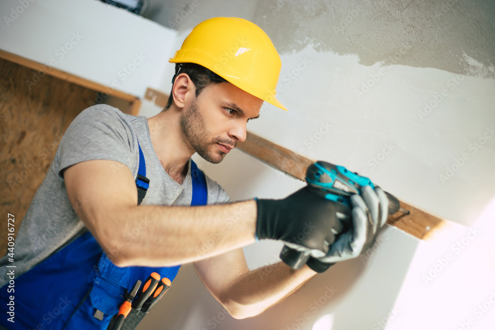 Young home repair male or worker busy with house renovation, holds building equipment, wears casual working clothes in the new build Young home repair male or worker busy with house renovation, holds building equipment, wears casual working clothes in the new build