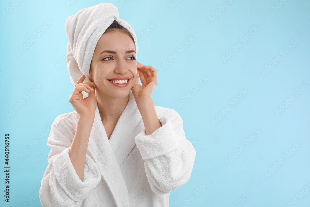 Beautiful young woman with hair wrapped in towel after washing on light blue background. Space for text Beautiful young woman with hair wrapped in towel after washing on light blue background. Space for text