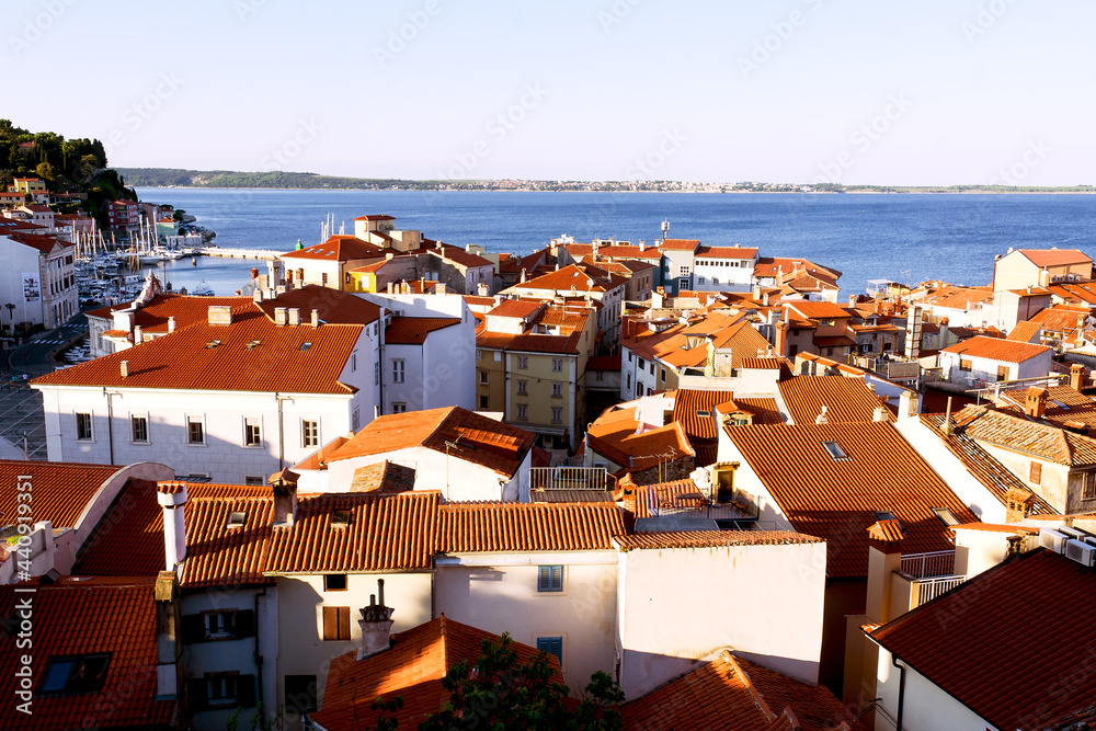 Scenic view of red roofs of the historical center of old town Piran with main church against the sunrise sky and blue Adriatic sea. Aerial view, coast of Slovenia. 