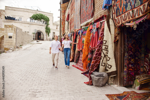Couple in love buys a carpet and handmade textiles at an oriental market in Turkey. Hugs and cheerful happy faces of men and women