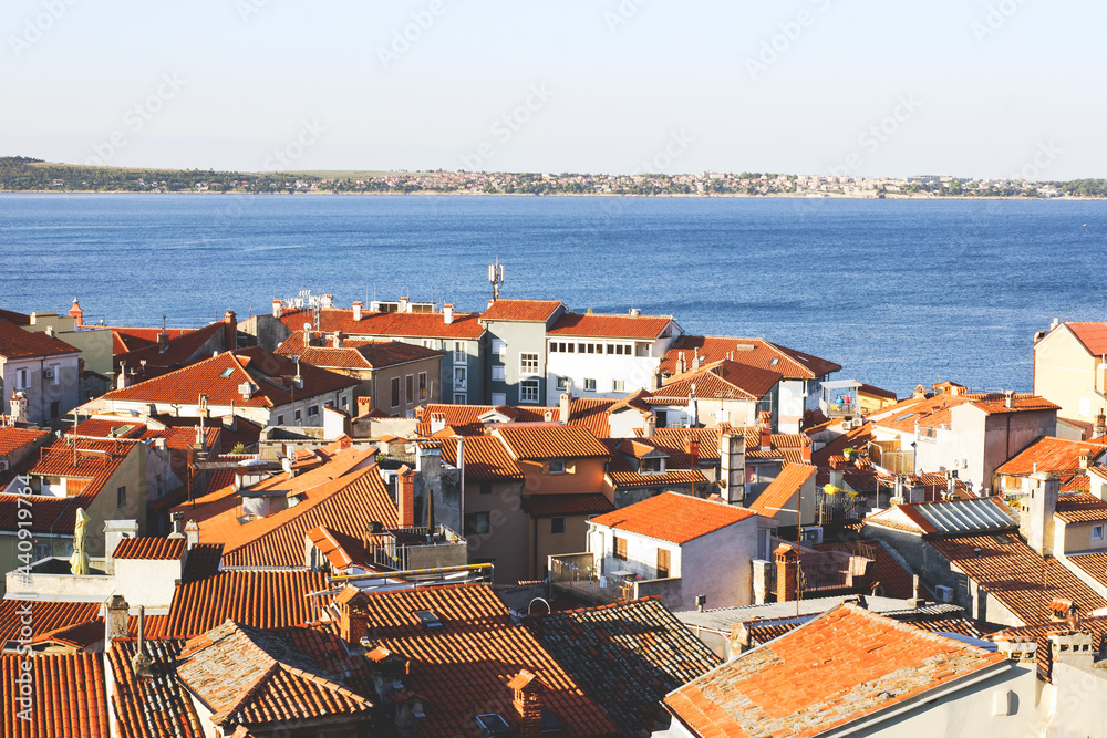 Scenic view of red roofs of the historical center of old town Piran with main church against the sunrise sky and blue Adriatic sea. Aerial view, coast of Slovenia. 