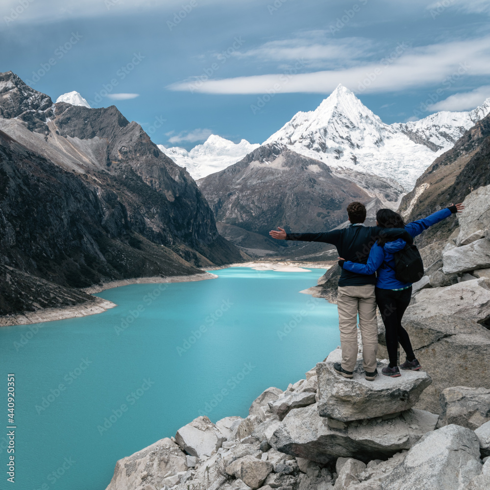 Couple with open arms looking at the amazing Lake Paron located in Cordillera Blsanca, Peru