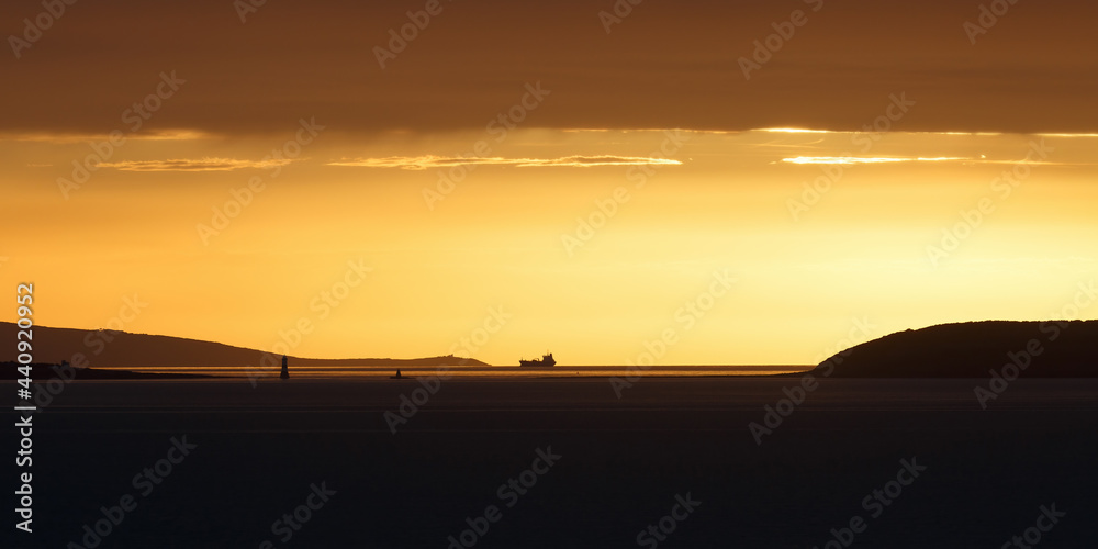 Sunset over the Irish Sea from Penmaenmawr, Wales with a silhouette containers ship on the horizon. Concept is Peace and serenity