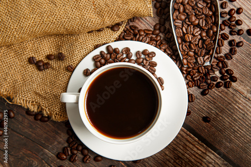 Cup of coffee and coffee beans on old wooden background
