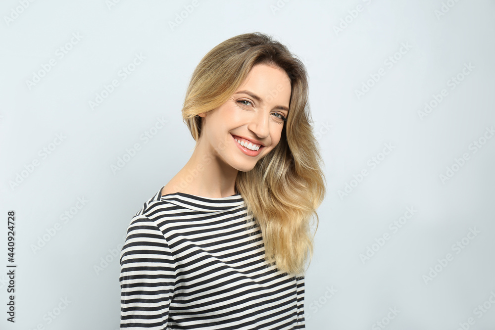 Portrait of happy young woman with beautiful blonde hair and charming smile on light background Portrait of happy young woman with beautiful blonde hair and charming smile on light background