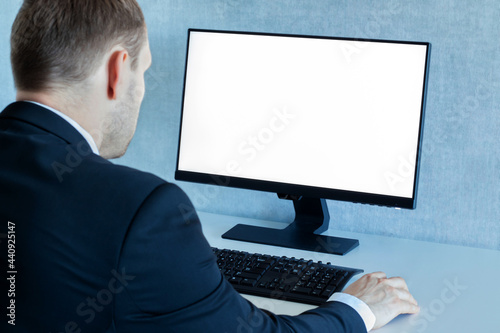 A man in a business suit works at a computer in the office.
