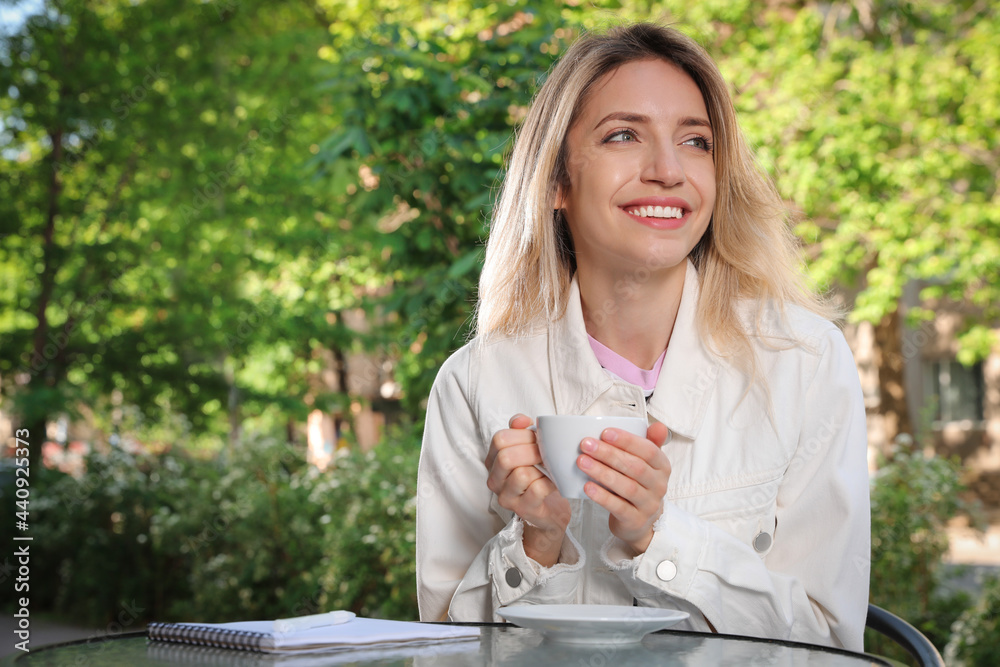 Happy young woman with cup of coffee enjoying early morning in outdoor cafe Happy young woman with cup of coffee enjoying early morning in outdoor cafe