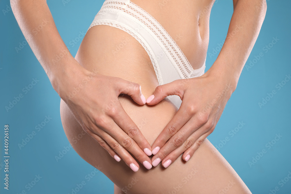 Closeup view of slim woman in underwear showing heart on light blue background. Cellulite problem concept