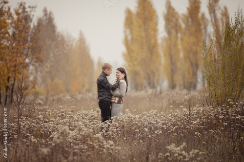 couple on autumn walk outdoors. Two lovers are hugging in autumn garden. Love and tender touch. Foggy cloudy day filled with the warmth of love. Beautiful autumn landscape for romantic date. 