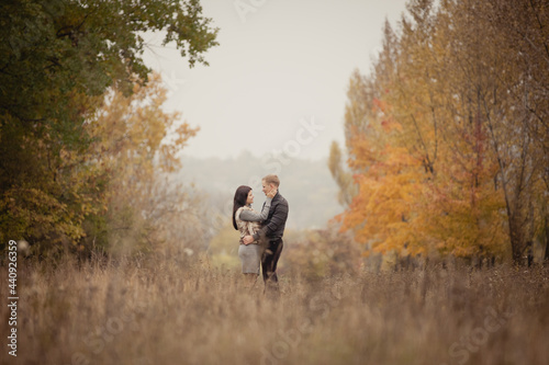 couple on autumn walk outdoors. Two lovers are hugging in autumn garden. Love and tender touch. Foggy cloudy day filled with the warmth of love. Beautiful autumn landscape for romantic date. 