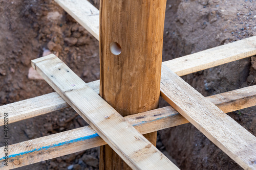 A wooden log fixed with struts in a pit, before pouring concrete
