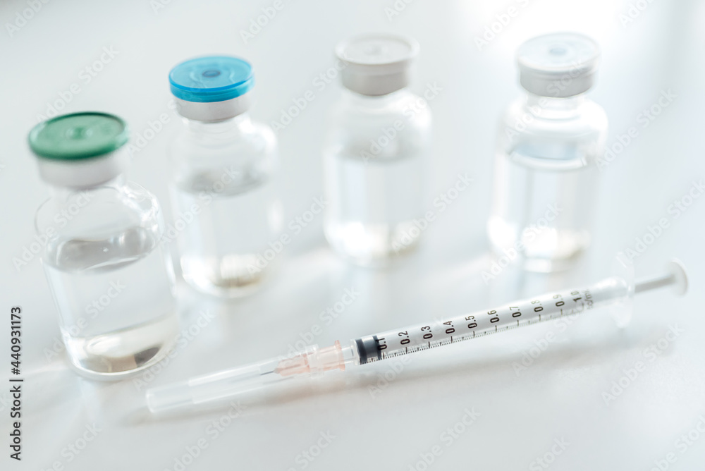 Bottles of vaccine vial and syringe on the white table. Bottles of vaccine vial and syringe on the white table.